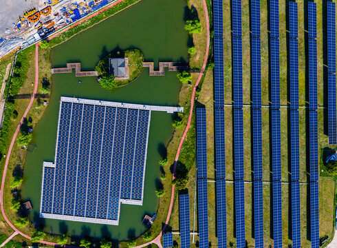 floating and ground-mounted solar panels beside green pond