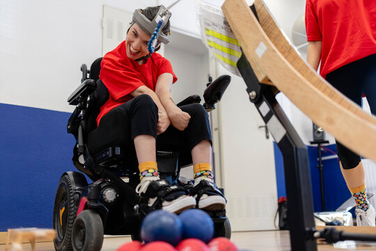 Smiling young woman playing boccia using assistive devices