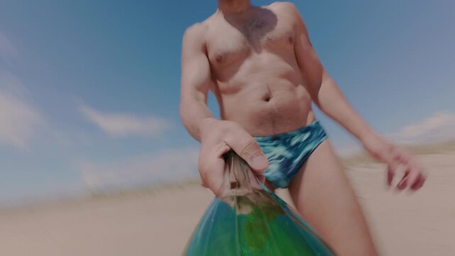 The guy is juggling a plastic bottle, tossing it in several turns. A juggler trains on the beach with a bottle. Active recreation on the beach during the bathing season.
