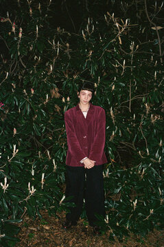 Stylish woman stands among dark green plants at night. Vintage outfit