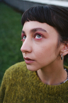 Young woman gazes upward in a green sweater outdoor