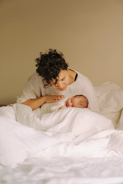 Caring mother gently stroking her sleeping newborns back 