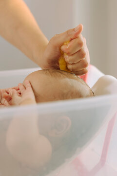 Close-up of parent washing baby's head with a yellow sponge