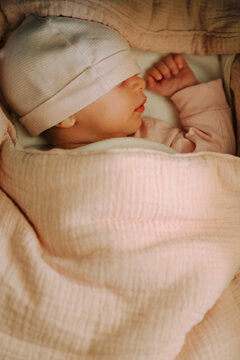 Sleeping newborn baby wrapped in a pink muslin blanket