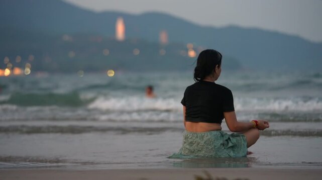 Woman meditating on beach shoreline with sea waves and Lady Buddha in Da Nang, Female practicing mindfulness by ocean at sunset with coastal mountains 4k