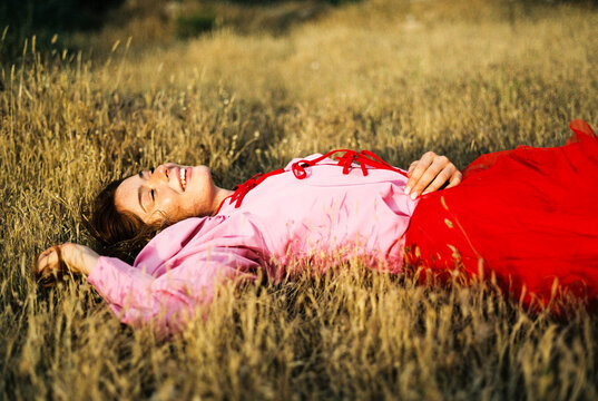 Happy woman laughing lying in field grass