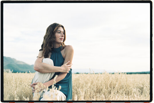 Woman sitting in a golden oat field