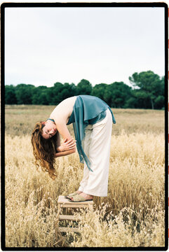 Woman bending over on stool in golden field