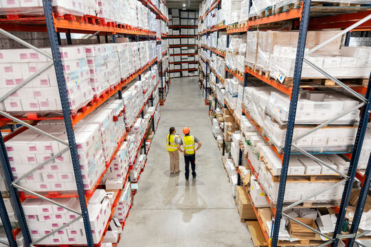 Workers managing inventory in large logistics warehouse