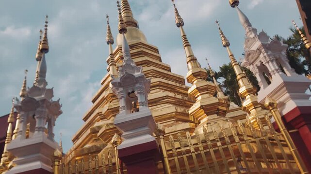 Golden Buddhist temple with ornate pagoda and spires in Chiang Mai, Traditional Thai shrine architecture with gilded stupa and cultural landmark, 4k spinning video