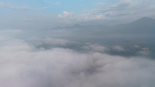 Aerial view reveals clouds swirling over mountain peaks at Lenggong, Perak