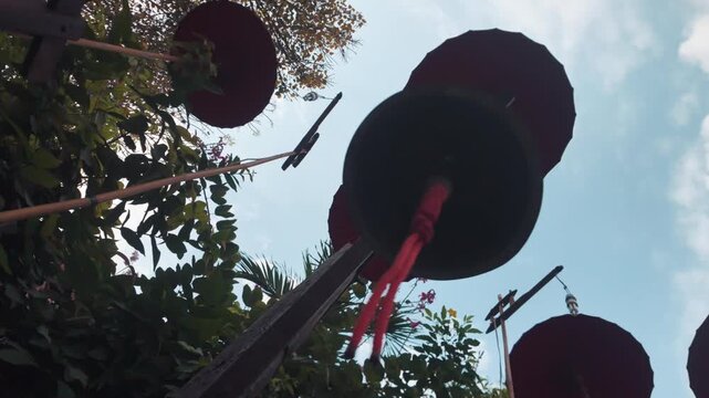 Temple bell and umbrellas viewed from below in Buddhist temple Thailand, Upward perspective of sacred bell and traditional umbrellas in tropical temple garden 4k