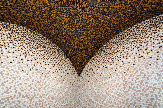 Symmetrical mosaic tile ceiling corner with gold gradient pattern, luxury hammam spa architecture detail, abstract mosaic tile pattern in gold and beige gradient
