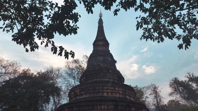 Ancient stupa at Wat Umong temple surrounded by trees Thailand, Buddhist pagoda rising above forest with peaceful spiritual atmosphere 4k