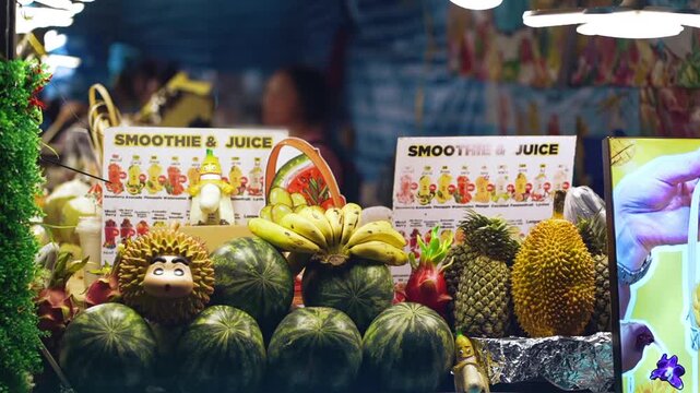 Fresh fruit smoothie and juice stall with tropical display at asian night market, Colorful fruit stand with bananas, pineapple, watermelon and durian for healthy drinks 4k