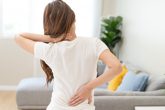 Pain body muscles stiff problem, asian young woman painful with back, neck ache from work hand holding massaging rubbing shoulder hurt, sore sitting on bed in room at home. Health care and medicine.