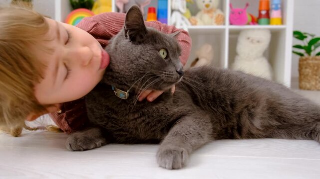 A child plays with a cat at home. Selective focus.