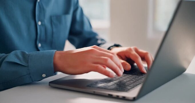 Businessman hands typing on a laptop keyboard at a desk