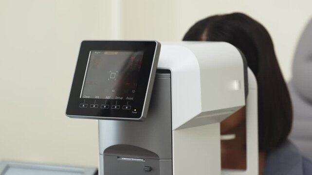 Young woman undergoing vision diagnostics with an autorefractor in a modern ophthalmology clinic. Concept vision diagnostics, ophthalmology, eye examination, optometry, preventive healthcare.
