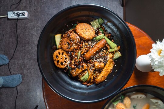 Spicy Noodle Bowl Delight: A delicious bowl of spicy noodles brimming with flavorful toppings and vegetables, served in a black ceramic bowl, offering a taste of authentic Asian cuisine.
