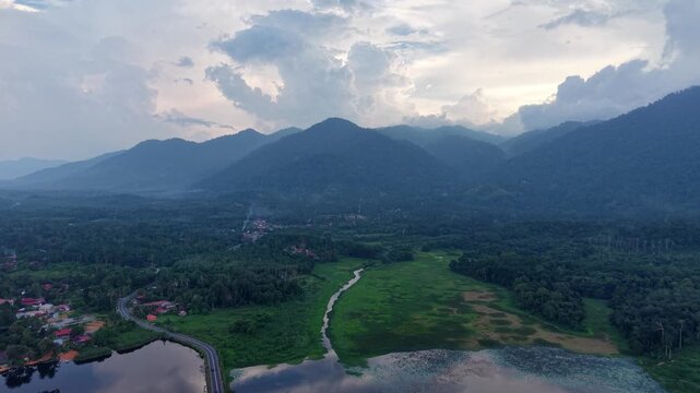 Drone view captures misty mountain peaks. Soft clouds drift over ridges at Tasik Raban