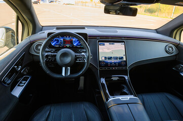 Naklejka premium Dashboard and cockpit interior layout of a modern luxury car featuring a digital instrument cluster, steering wheel, and a large multimedia navigation touchscreen display.