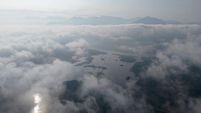 A peaceful aerial view showing islands surrounded by water, partially hidden under a thick layer of clouds and mist at Tasik Raban
