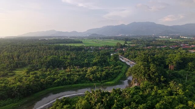 A stunning aerial view capturing a winding river flowing through dense green forest at Balik Pulau, Penang