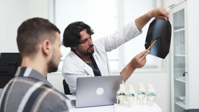 Traumatologist discussing diagnosis and treatment with a patient using an X-ray image. Concept orthopedics, traumatology, medical consultation, rehabilitation, musculoskeletal medicine.