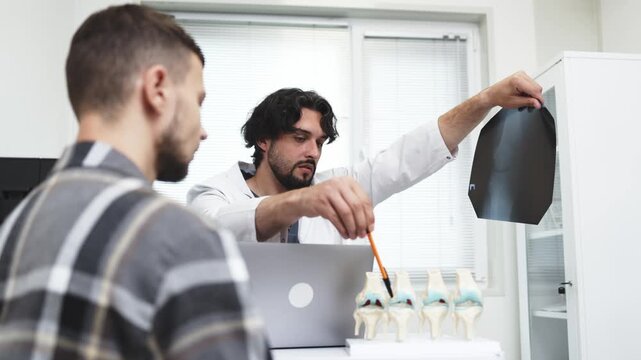 Traumatologist reviewing an X-ray image with a patient after diagnostic examination. Concept traumatology, orthopedic consultation, medical diagnostics, bone health, healthcare.