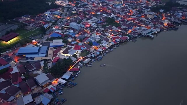 Dusk settles over a riverside village. Lights glow warmly from homes and shops at Sungai Udang, Penang