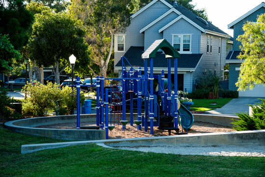 Bright blue playground equipment in a suburban neighborhood with townhouses