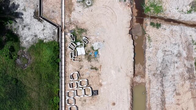 Aerial shot displays concrete blocks lined along a dirt path