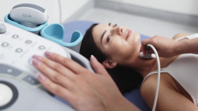 Close-up thyroid ultrasound procedure in a bright medical examination room. Concept thyroid diagnostics, endocrinology, medical imaging, clinical examination, healthcare.