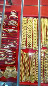 A luxurious close-up display of heavy 916 gold chain bracelets and necklaces neatly arranged vertically inside a red velvet jewelry box.