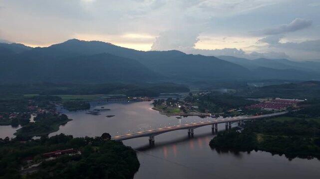 Aerial shot shows a river flowing through a valley. Bridge crosses the water, linking two sides at Tasik Raban