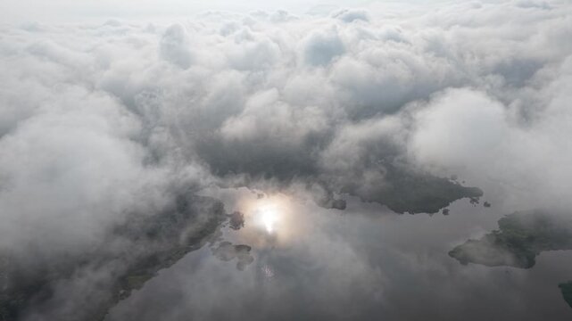 Aerial dense cloudy sky with soft mist and water reflections over a natural landscape at Tasik Raban