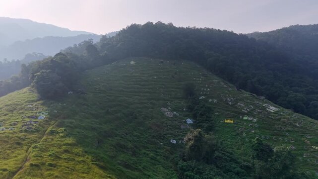 Drone panorama of terraced hillside cemetery nestled among misty mountains at sunrise at Kampar