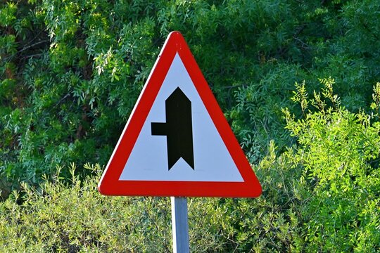 Warning road sign signaling a road merge from the left onto the main traffic lane. July 13, 2026