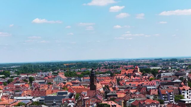 Spektakul&auml;re Weitwinkel-Luftaufnahme von Landau in der Pfalz unter blauem Sommerhimmel, die die dichte Altstadt, markante Kirchen und angrenzende gr&uuml;ne Parkanlagen zeigt.