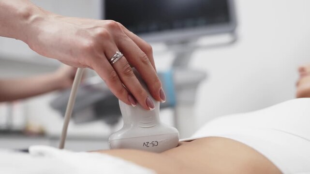 Medical professional performing an abdominal ultrasound examination for a young woman in a modern medical clinic. Concept ultrasound diagnostics, abdominal examination, medical imaging, preventive hea