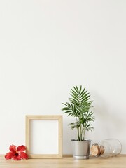 Fototapeta premium Blank wooden frame, potted palm, and red hibiscus flower