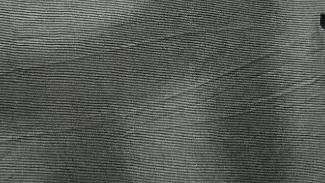 macro texture of black corduroy fabric showcasing fine ribbed details in a minimalist abstract flat lay