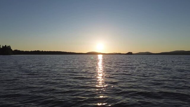 fast drone footage over a lake with a sunset with a drone that is speeding over the lake