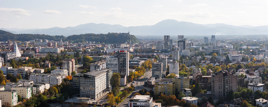 Aerial view shows Ljubljana, Slovenia with its urban skyline, historic buildings, and old castle on a clear day.