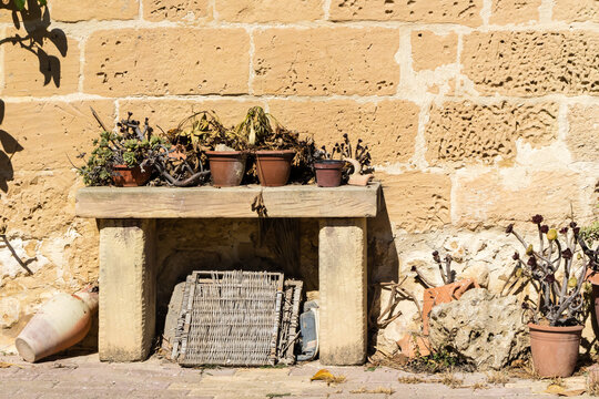 Rustic Stone Wall With Weathered Bench and Potted Plants in Sunny Mediterranean Courtyard