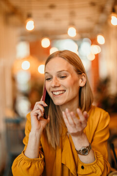 Woman talking on smartphone in cafe smiling