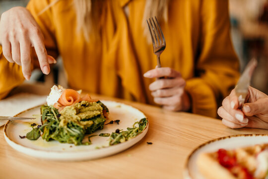 Woman enjoying healthy avocado toast with salmon for brunch