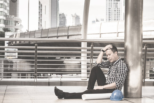 Asian engineer man who sitting on the floor in feeling sad because his business failed and unemployed. Business failed concept.
