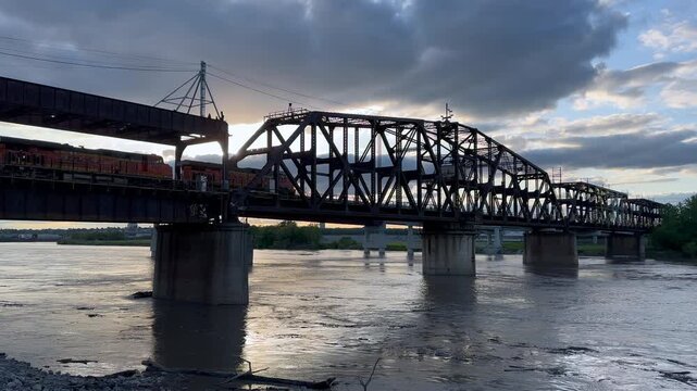 Low Angle View of BNSF Hannibal Bridge over the Missouri River in Kansas City. Cloudy Day with Train Passing Against the Sun. 4K.